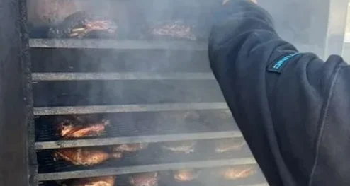 A dad checking meat in a smoker
